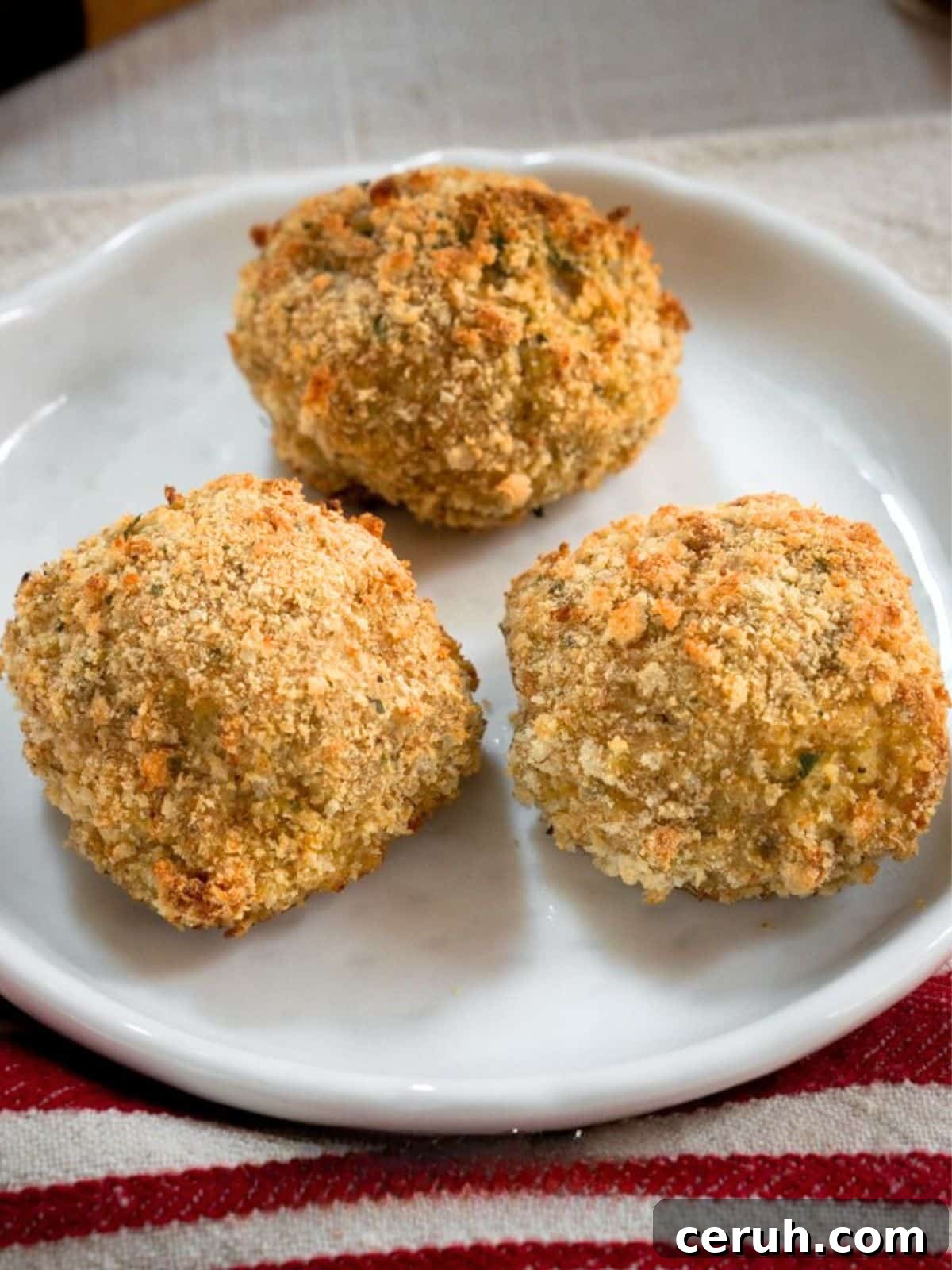 Three baked breaded meatballs on a plate - Hostess At Heart