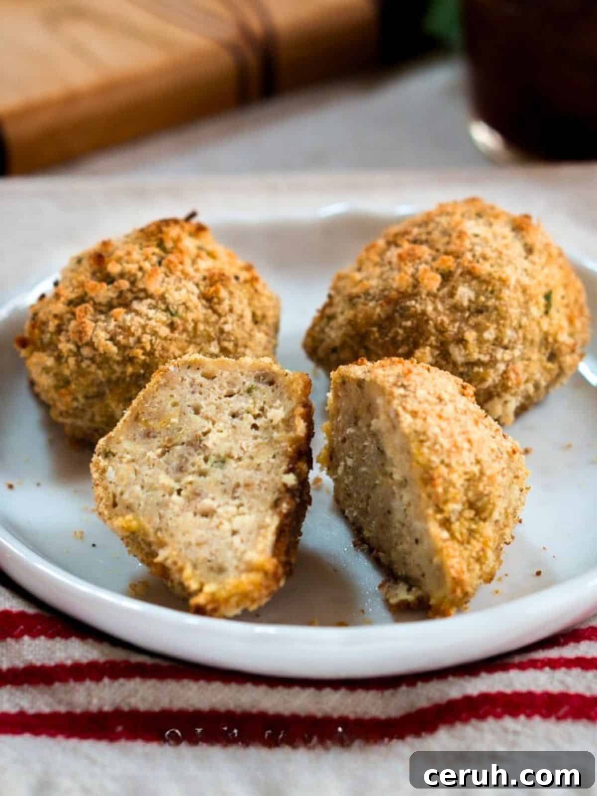 Three meatballs on a plate. The front one is cut in half. Hostess At Heart