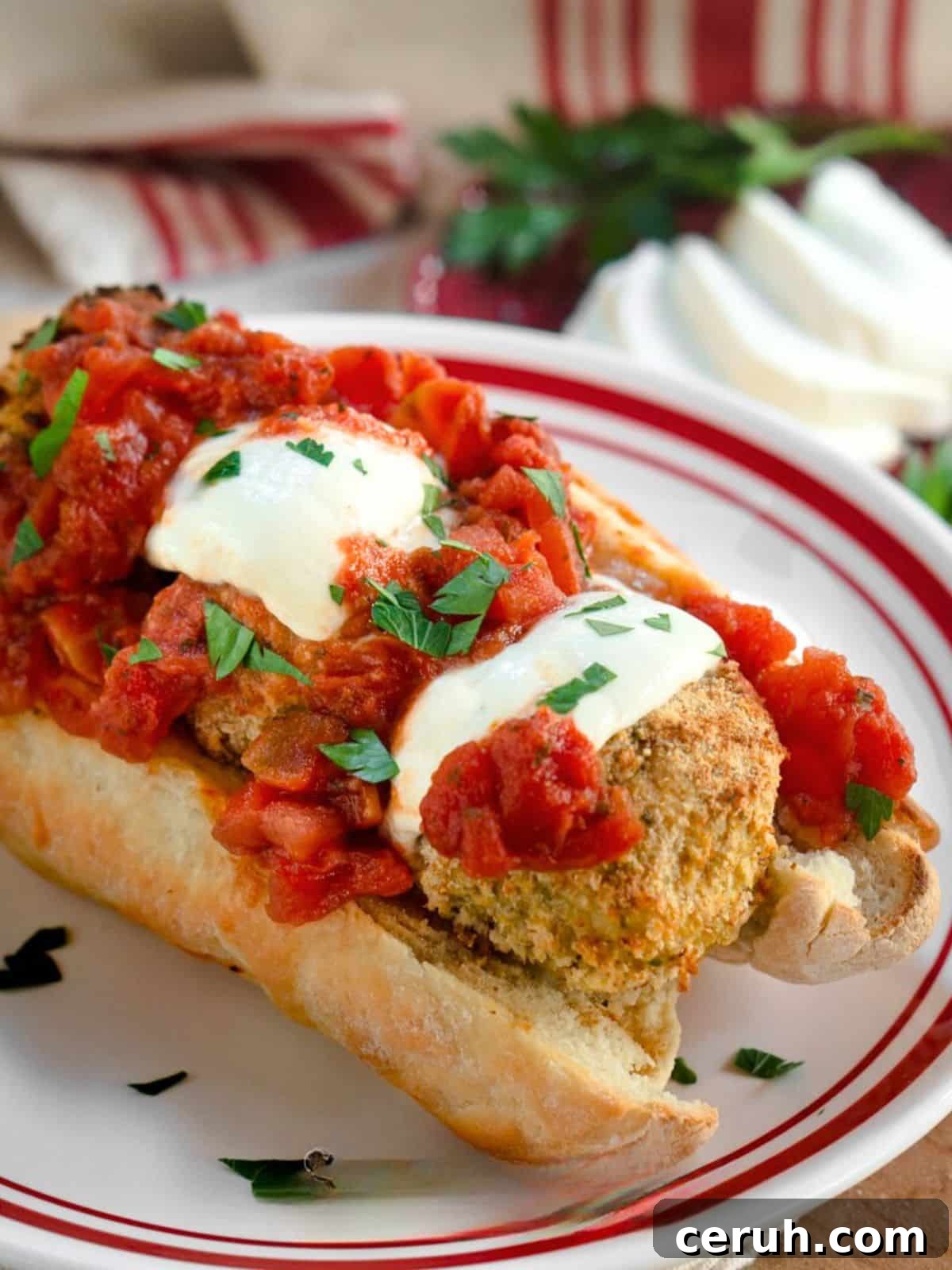 Tableview of a meatball sub sandwich topped with melted mozzarella, marinara, and fresh parsley. Hostess At Heart