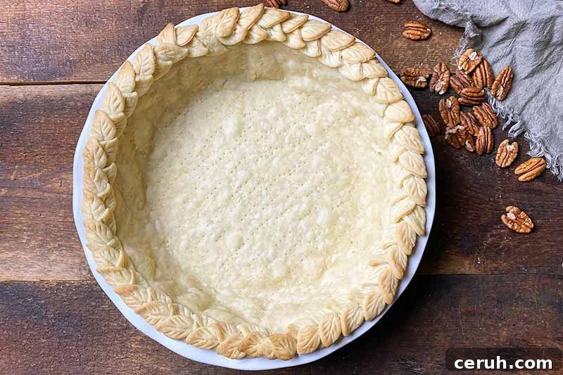 Horizontal image of a par-baked crust with decorations on the rim.