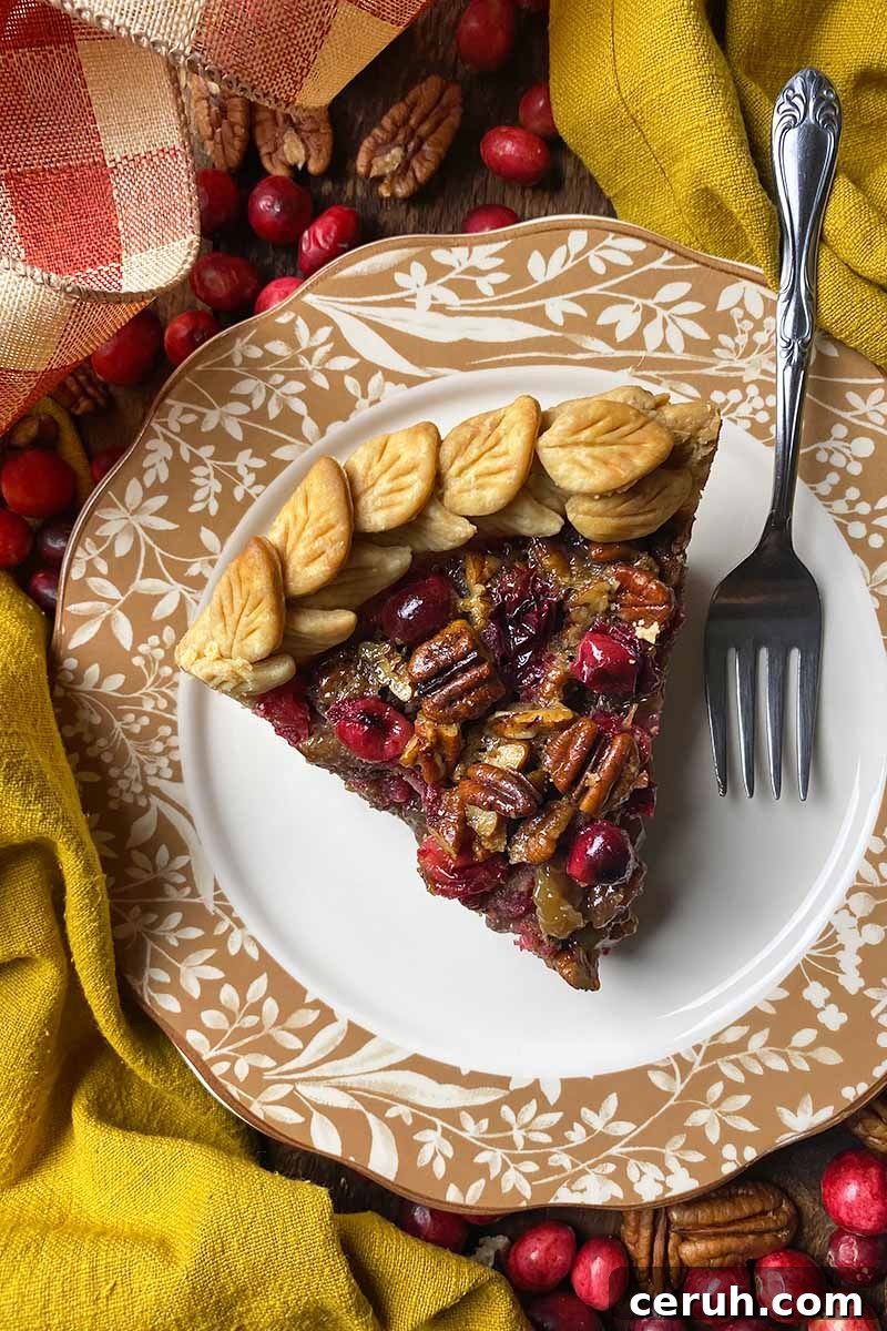 Vertical top-down image of a slice of pastry with a nut filling on a plate with a fork next to fall decor.