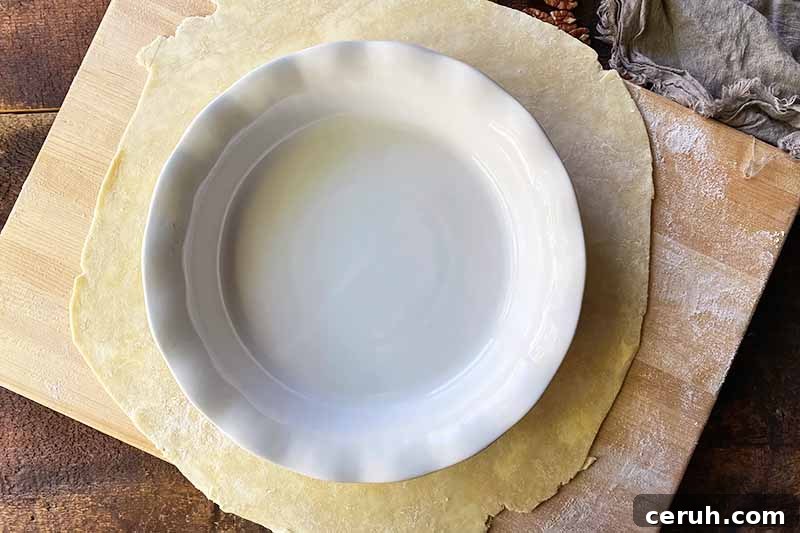 Horizontal image of rolling dough larger than the size of a circular casserole dish.