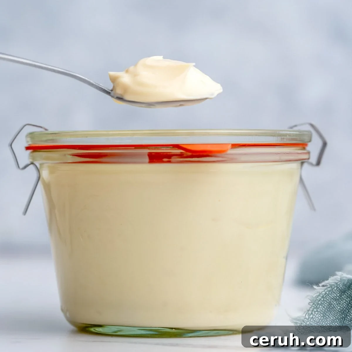 Finished homemade mayonnaise stored in a small glass jar with a red-handled lid, sealed and ready for refrigeration.