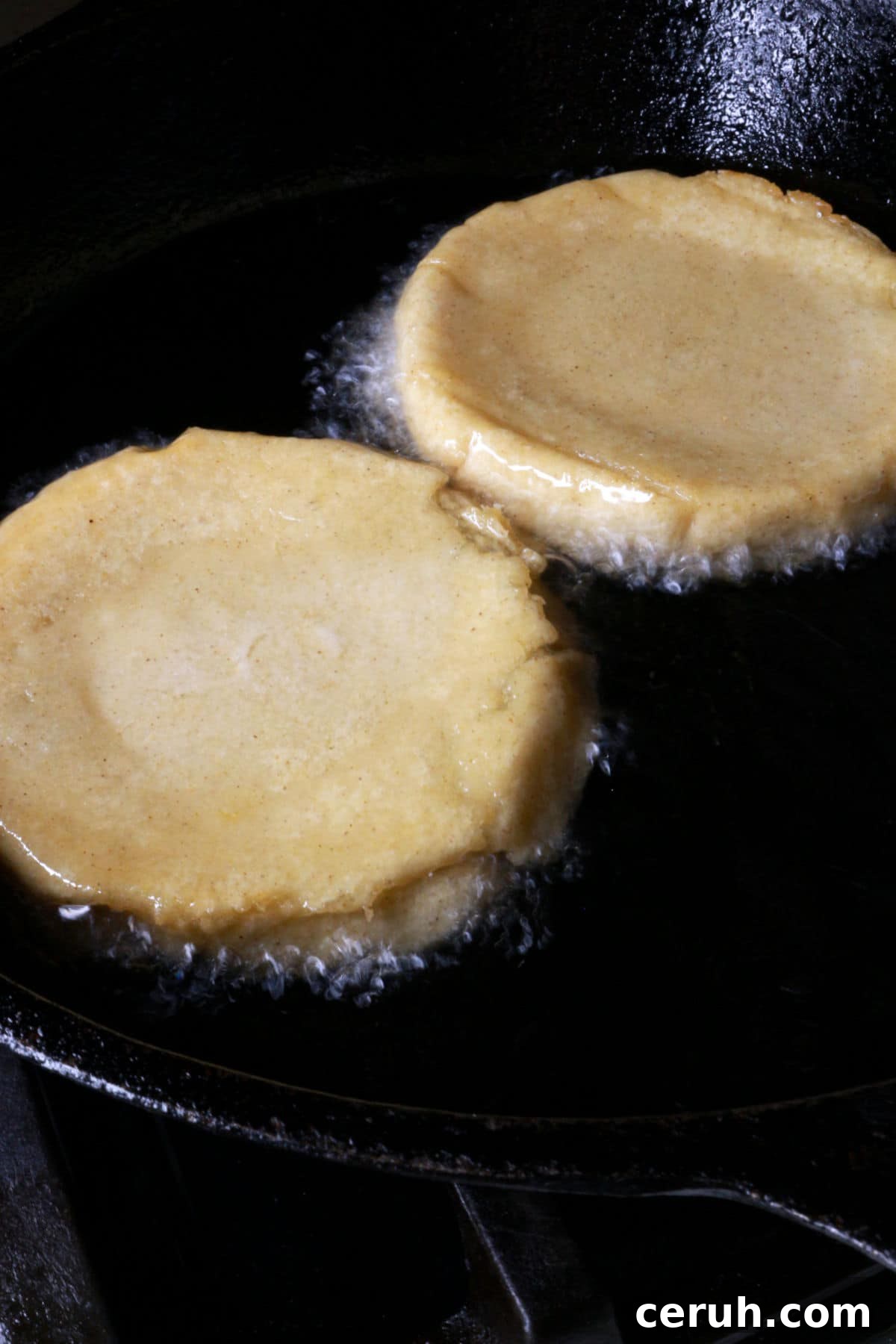 Two sopes face down in frying pan with oil.