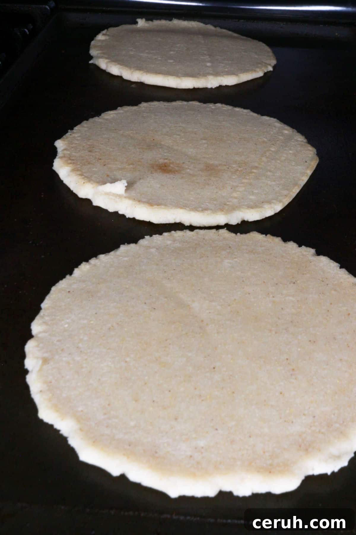 Three thick corn tortillas on a comal