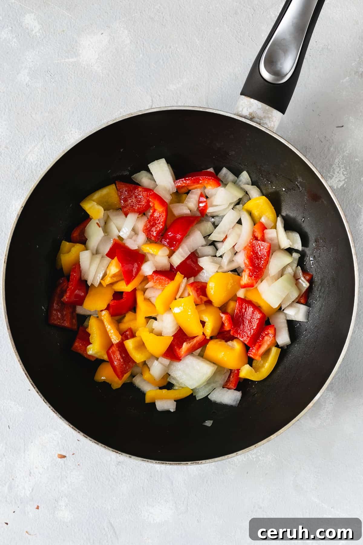 overhead shot of big frying pan with chopped onions and peppers