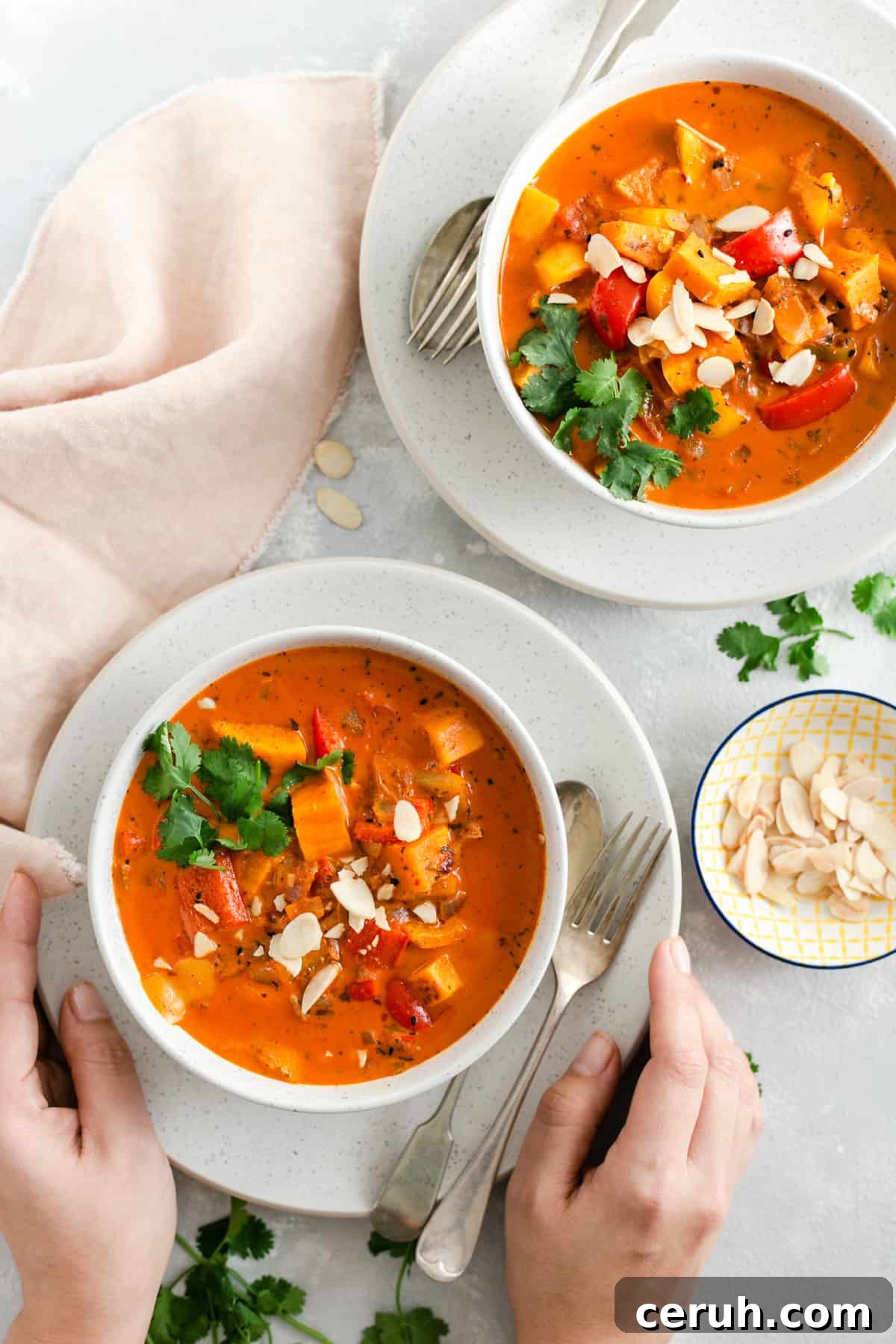 overhead shot of two bowls with sweet potato curry and side dish with toasted almonds