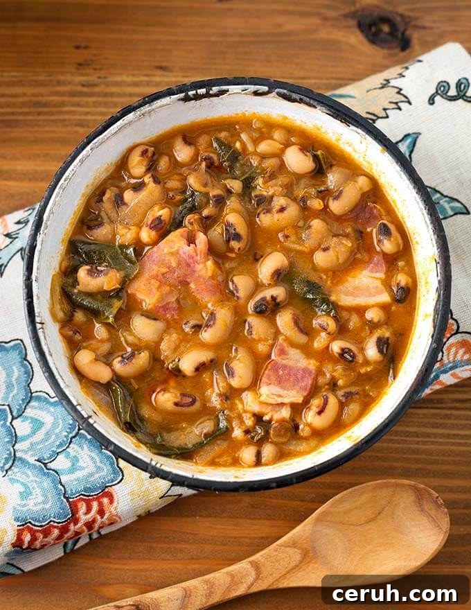 Black Eyed Peas in a white bowl with black rim on a floral napkin next to a wooden spoon