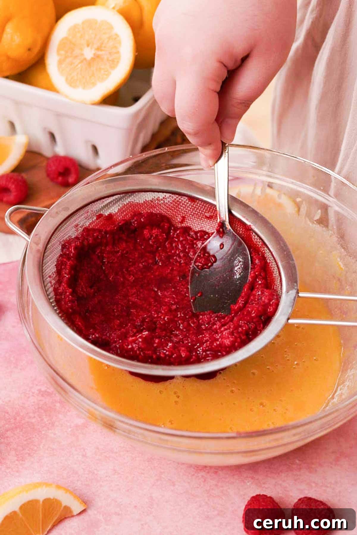straining defrosted raspberries into the lemon raspberry bar filling