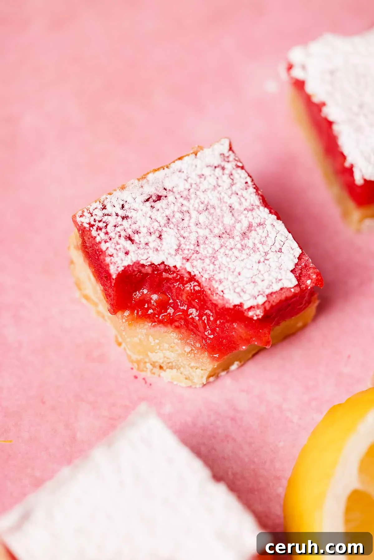 bitten lemon raspberry bar on pink countertop