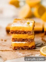 stacked lemon bars with graham cracker crust and powdered sugar