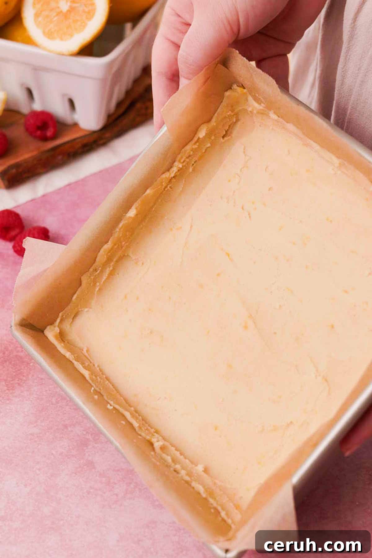 smoothing shortbread crust into square parchment lined baking pan