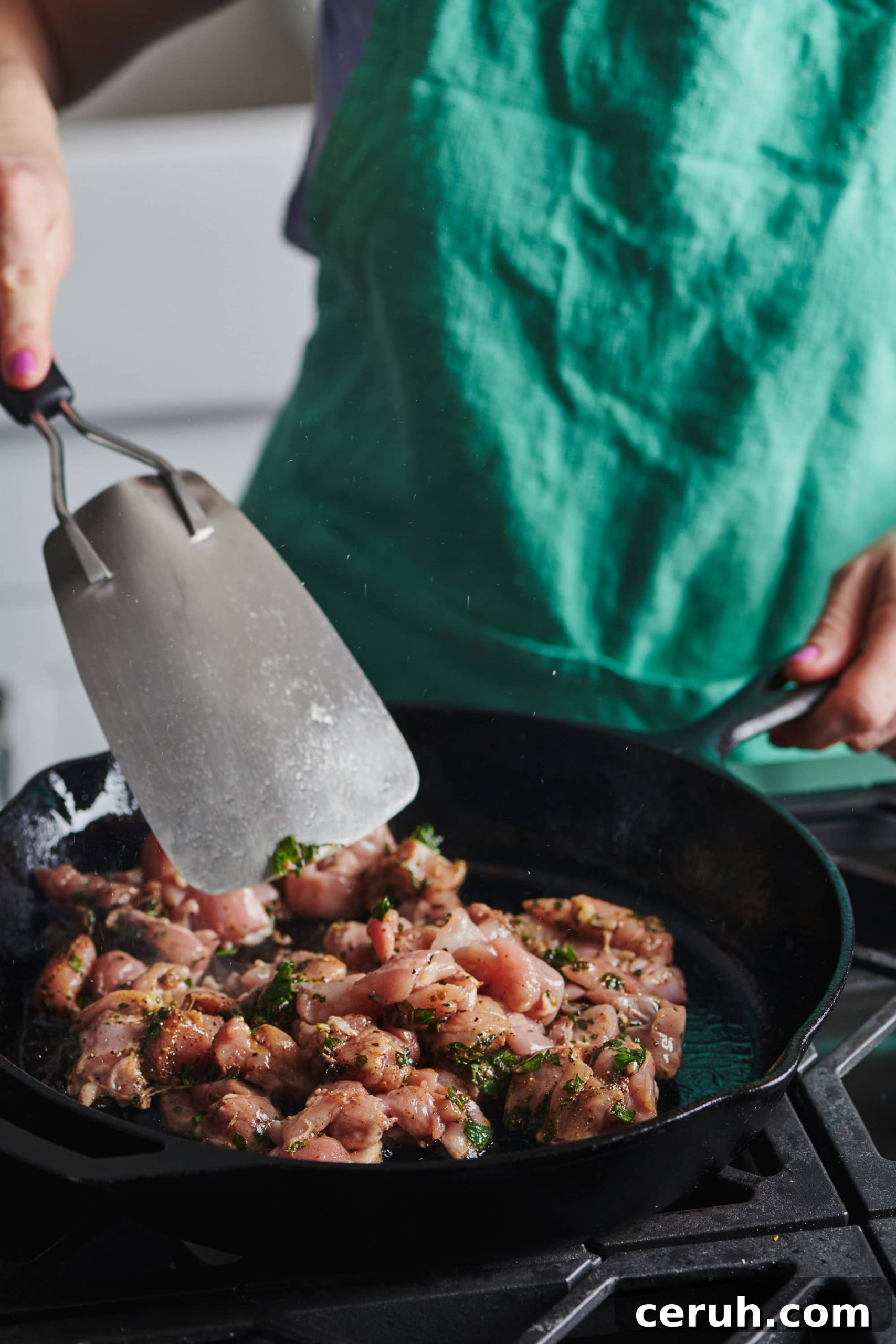 Metal spatula flipping Chicken Kawarma in a skillet.