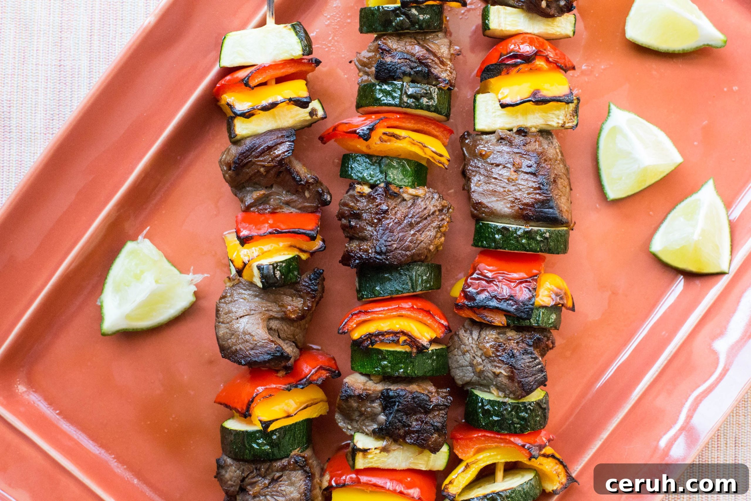 Broiled Beef Teriyaki Kebabs with Peppers, and Zucchini on an orange plate.