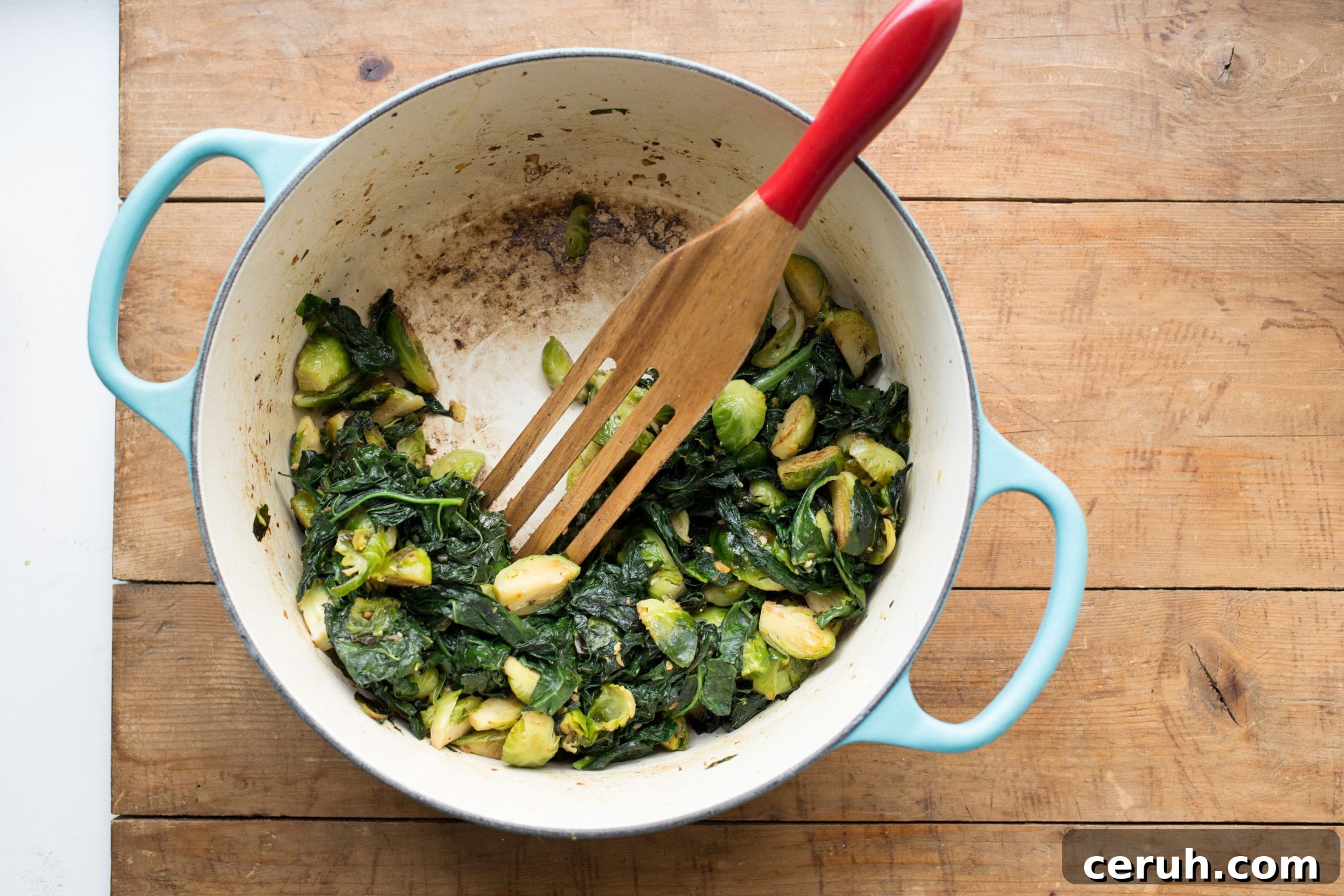 Sauteed Kale and Brussels Sprouts with Bacon in pot with spatula.
