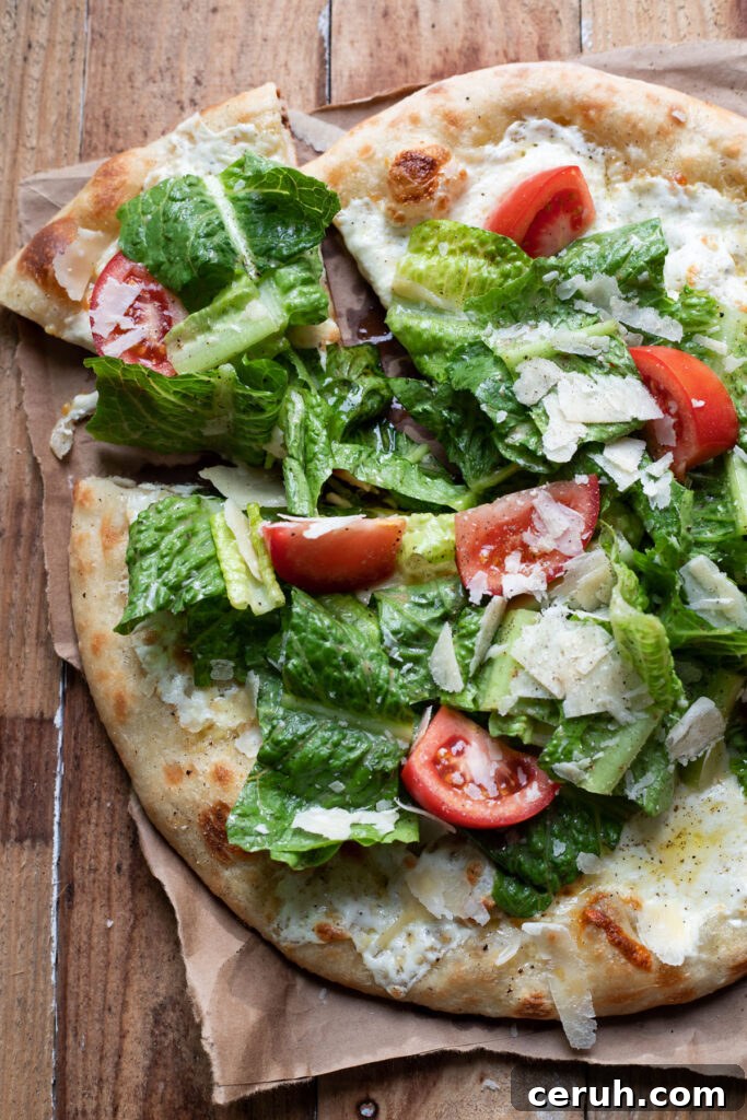 cheese pizza with caesar salad and tomatoes on top