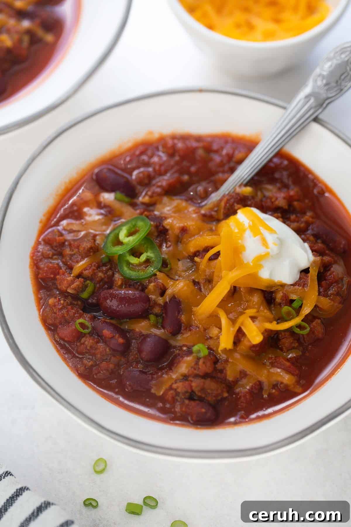 gluten-free chili in white bowl topped with sour cream and cheese