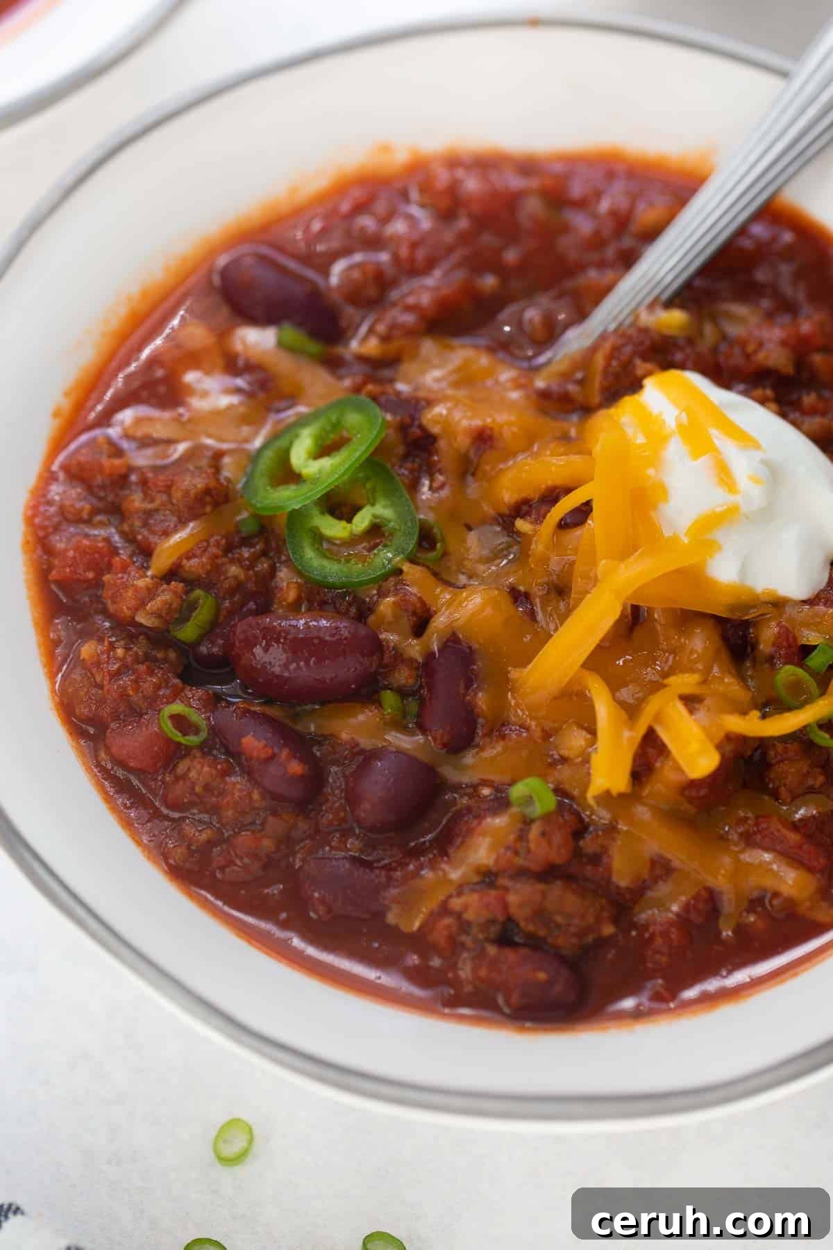 close up shot of gluten-free chili in white bowl topped with sour cream and cheese