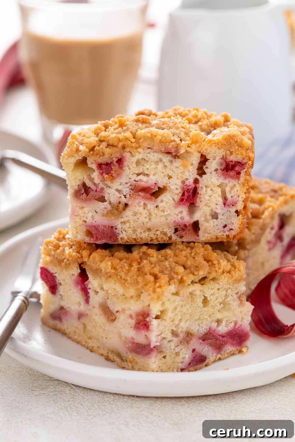 Two slices of rhubarb cake stacked on a white plate.