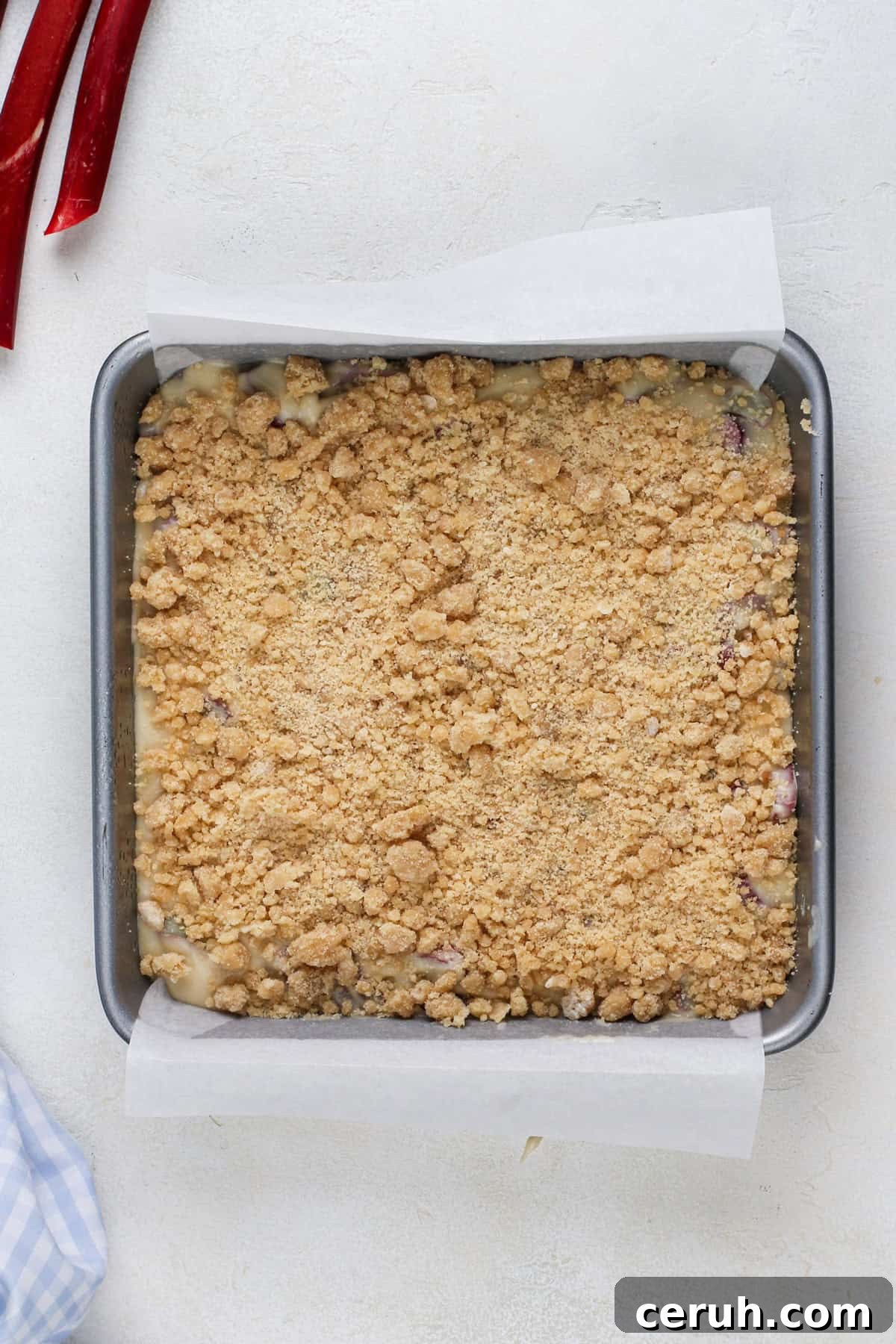 Unbaked rhubarb streusel cake in a cake pan, ready to go in the oven.