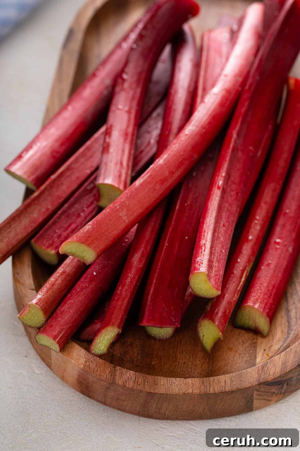 Stalks of fresh rhubarb on a wooden board.