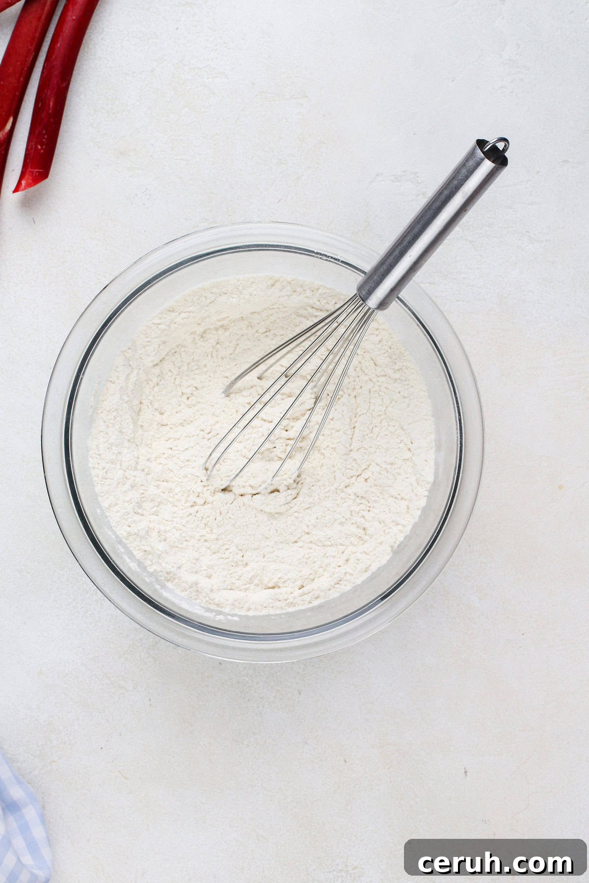 Dry cake ingredients whisked in a glass bowl.