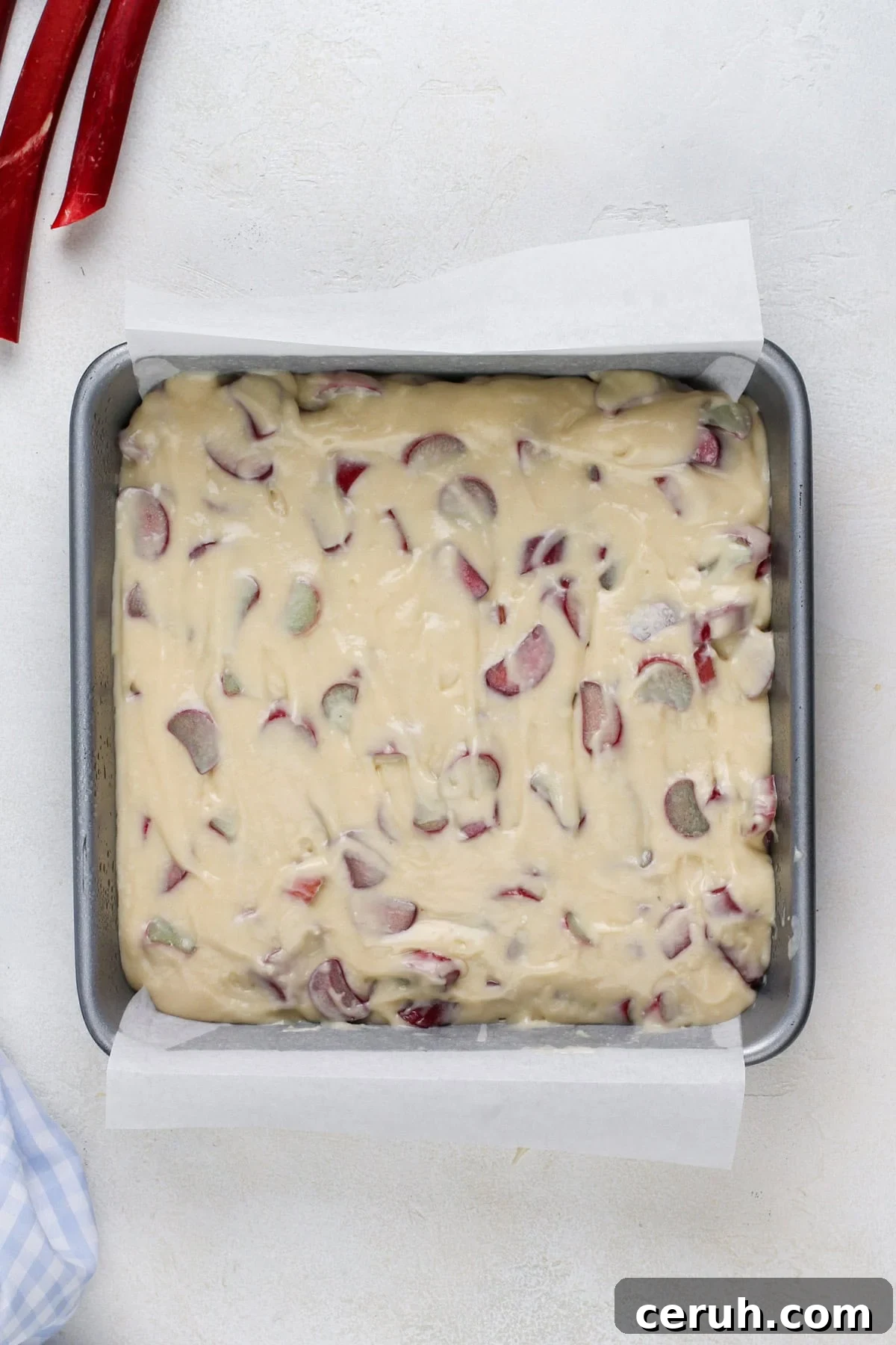 Rhubarb cake batter spread into a cake pan.