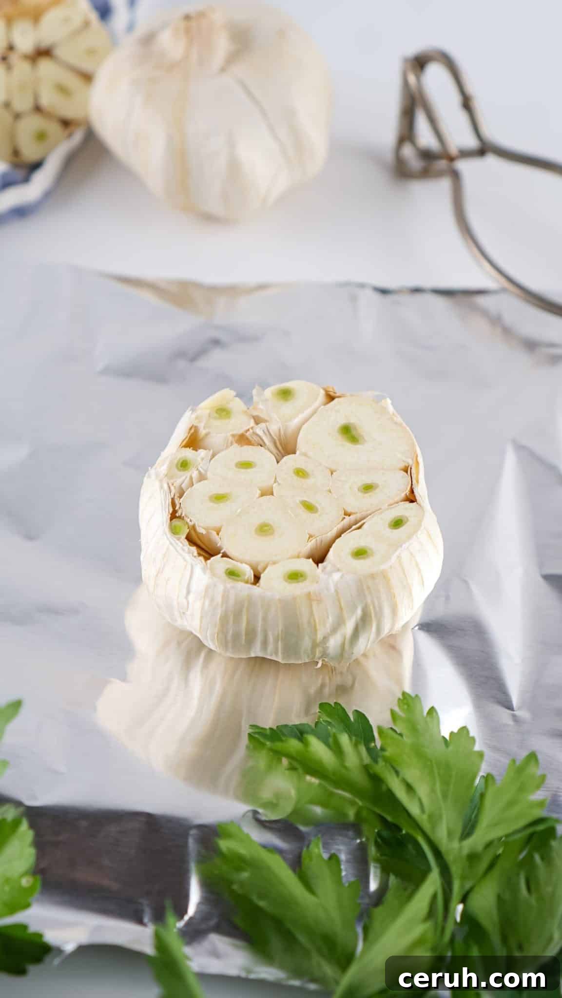 a garlic bulb cut in half and resting on a sheet of aluminum foil