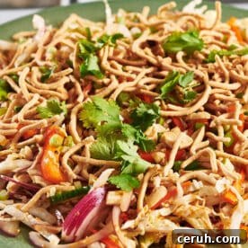 Chinese chicken salad piled on green plate.