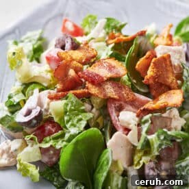 Chopped salad with chicken and blue cheese on white plate.