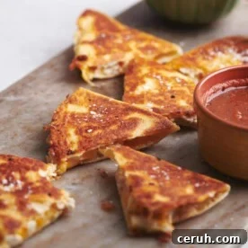Cut Rotisserie Chicken and Cheese Quesadillas on a board with bowls of dip.