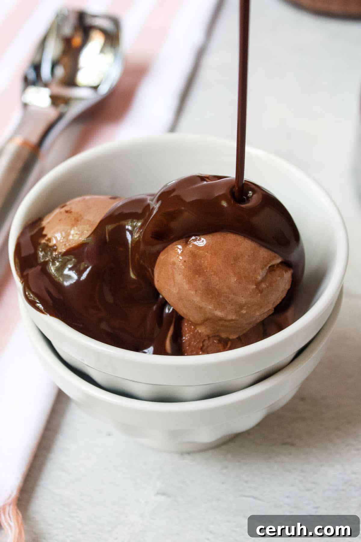 Pouring chocolate syrup over scoops of Ninja Creami Chocolate Protein Ice Cream in a small bowl