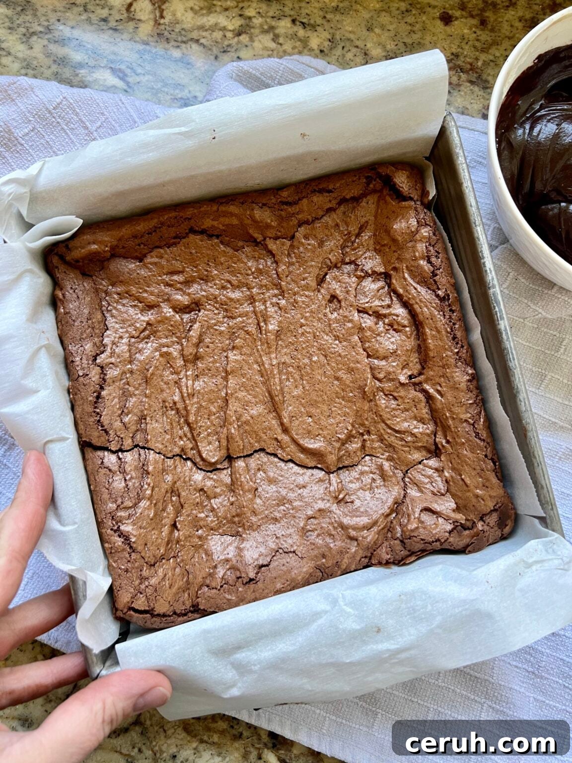 A baked square pan of brownies sits on a countertop.