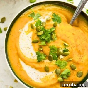 A bowl of pumpkin and sweet potato soup topped with chopped cilantro and pumpkin seeds.