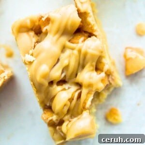 A paleo apple pie bar with a bite out of it and pieces of cooked apples beside it.