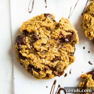 A paleo pumpkin chocolate chip cookie on a baking sheet with sea salt on top of it.