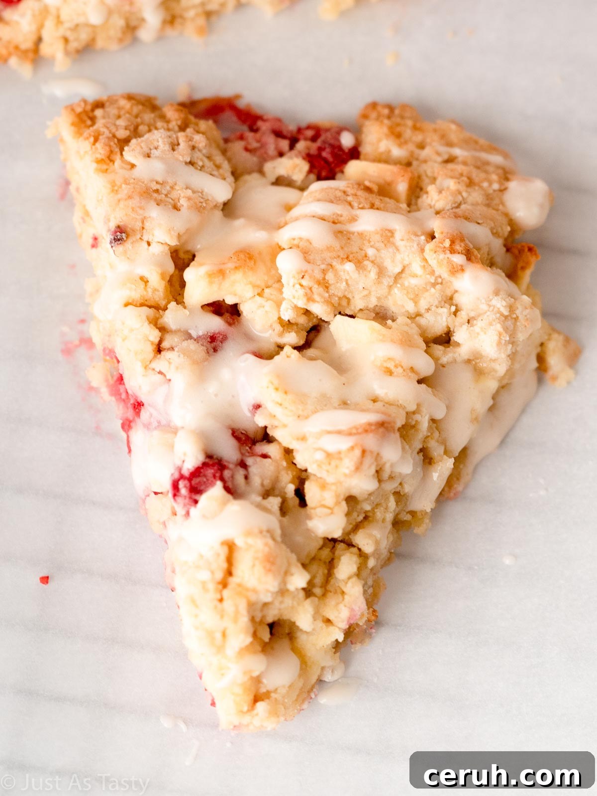 Close-up of a glazed white chocolate raspberry scone.