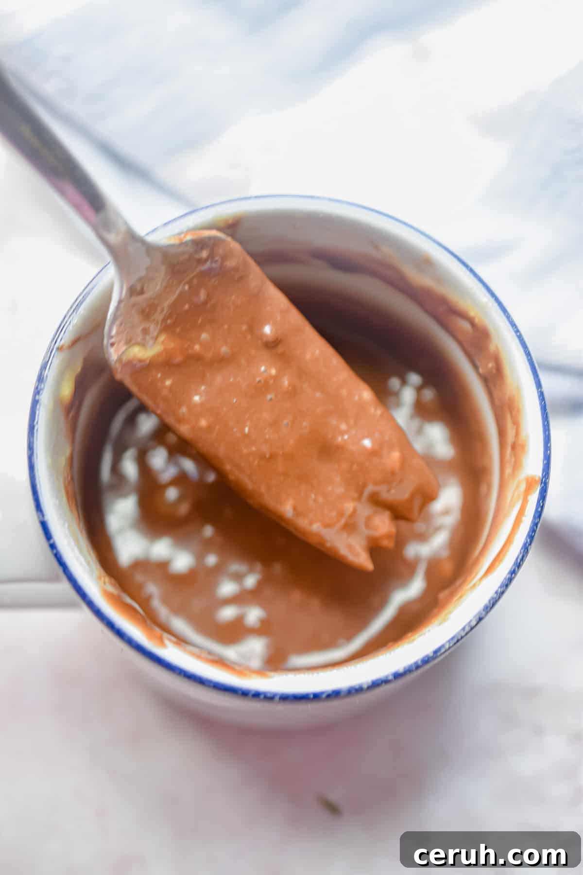 The batter for the Nutella mug cake is being lifted out of the mug.