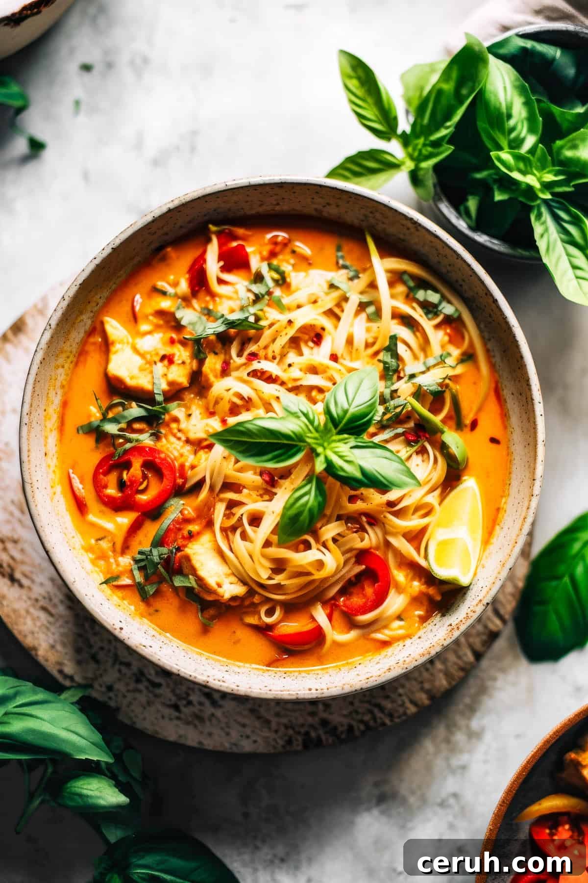 Red Curry Thai noodles with chicken and basil in a white bowl.