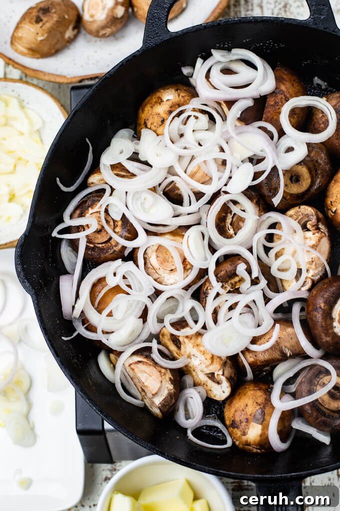 Mushrooms and sliced shallots are sautéing in a cast iron skillet. Bowls of mushroom, garlic, butter and shallots sit around the pan.