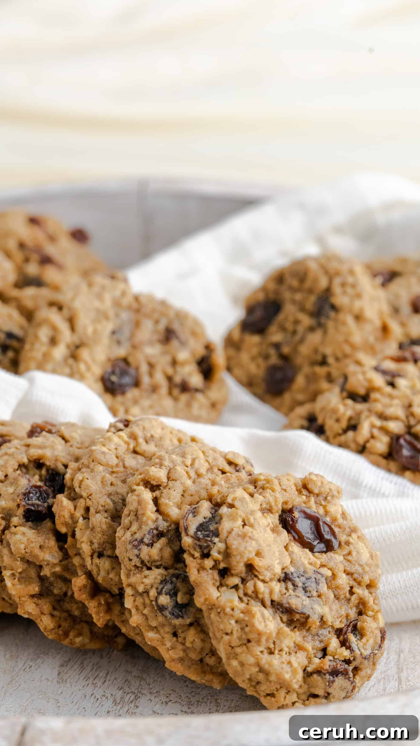 Soft Chewy Oatmeal Raisin Cookies That Stay Moist Longer 2 A wooden platter of oatmeal raisin cookies with white fabric.