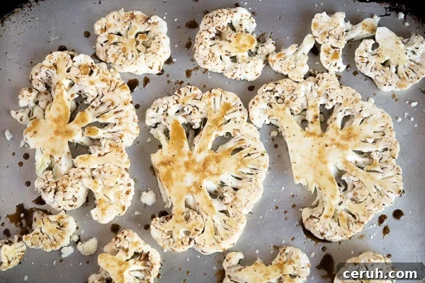 Uncooked cauliflower steaks coated with marinade on sheet pan