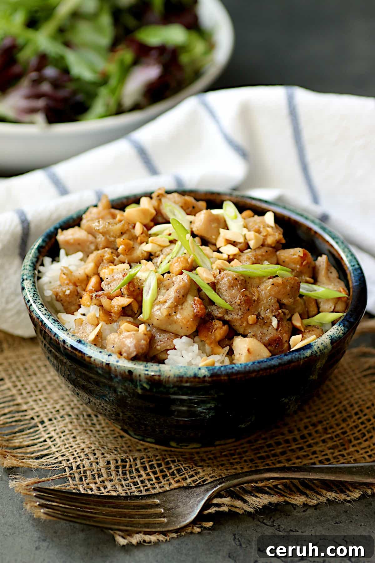 Thai Rama Chicken in Creamy Peanut Sauce Recipe 6 Ginger peanut chicken over rice in a blue, pottery bowl.
