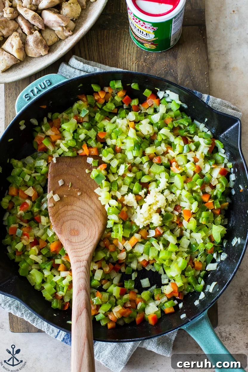Overhead photo of a skillet of cooked peppers and onions with a wooden spoon
