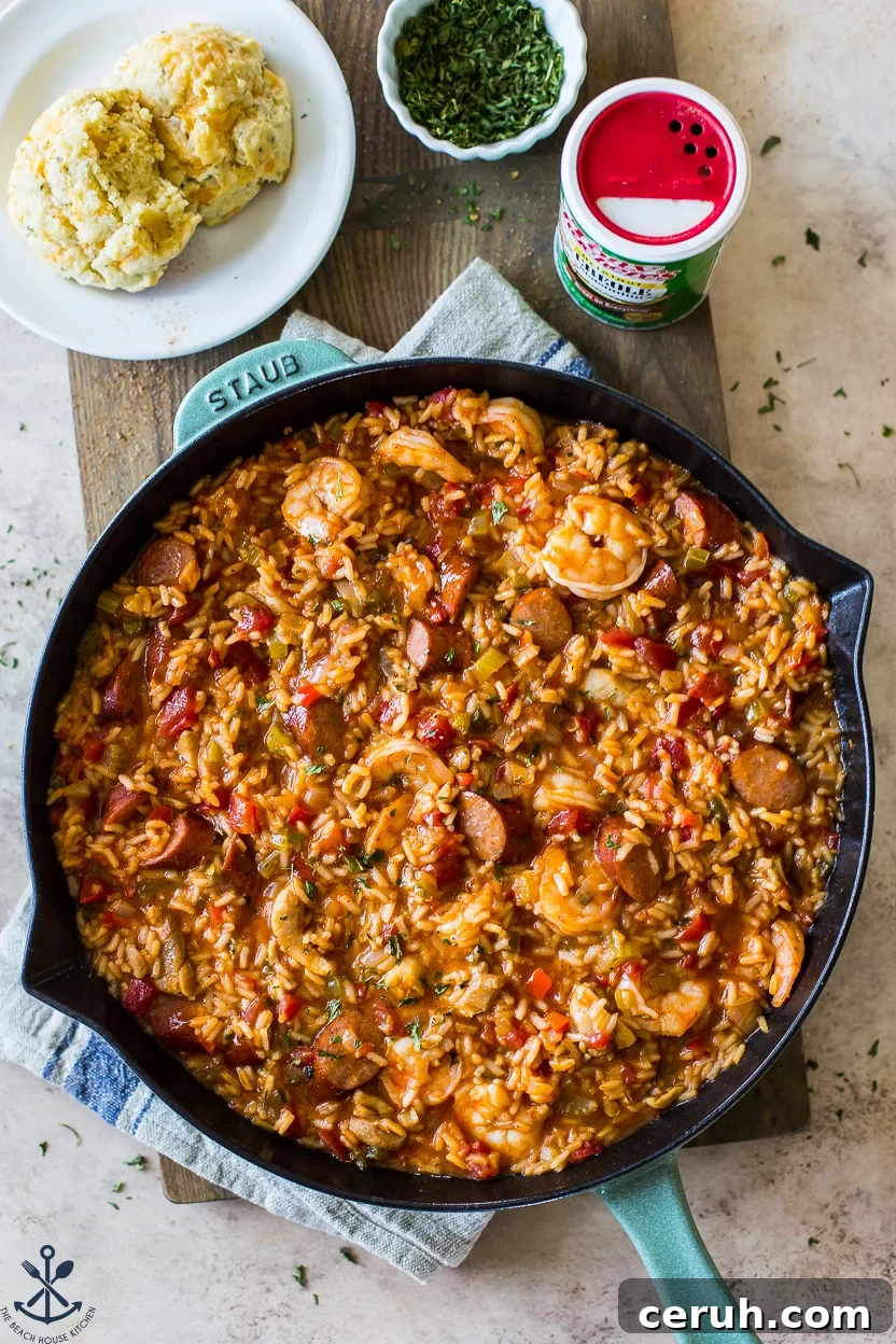 Overhead photo of a skillet of jambalaya with two biscuits on a plate off to the side