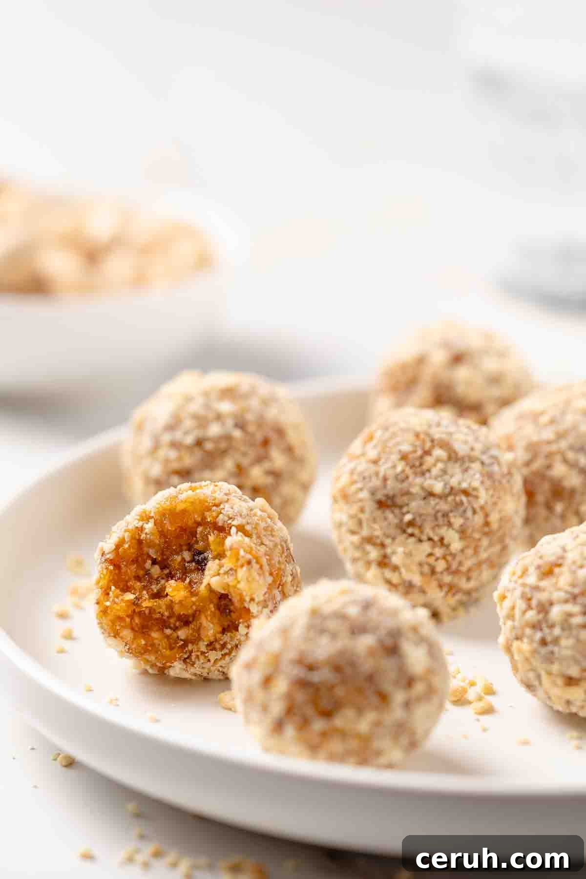 apricot balls on a white plate with one ball having a bite taken out.