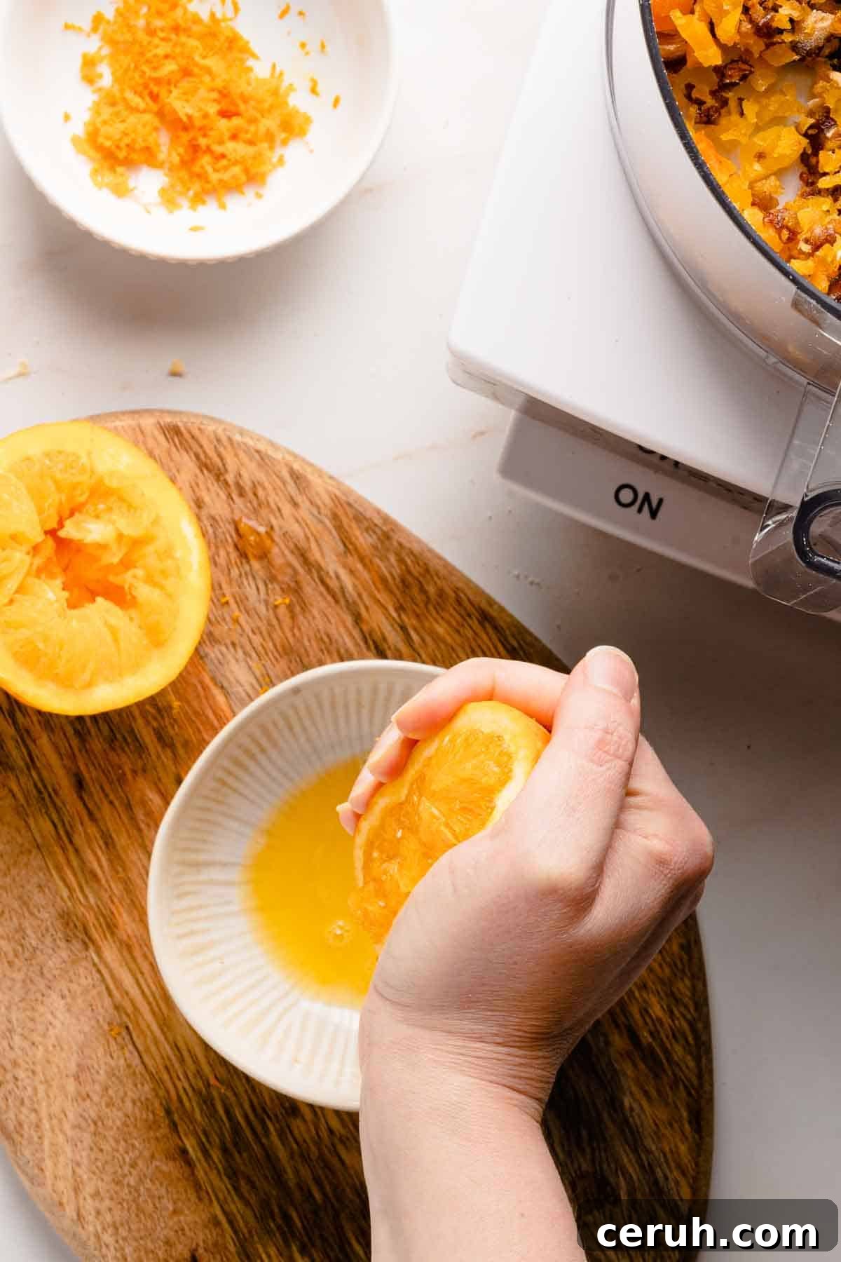 orange half being squeezed over small bowl.