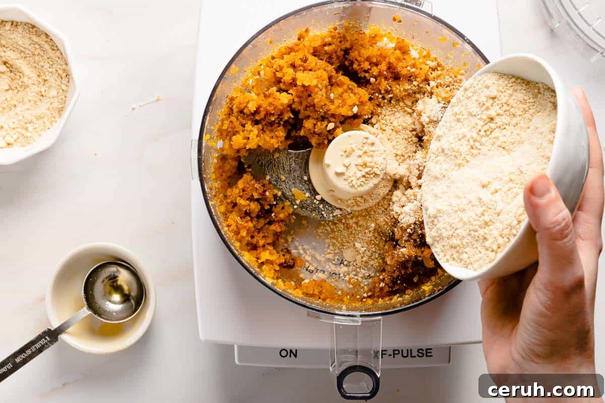 chopped cashews being poured into food processor with dried fruit inside