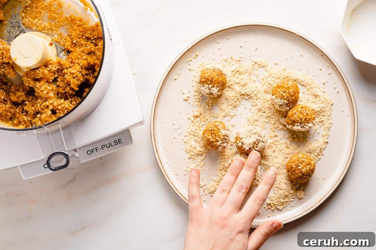 bliss balls being rolled in chopped nuts on plate