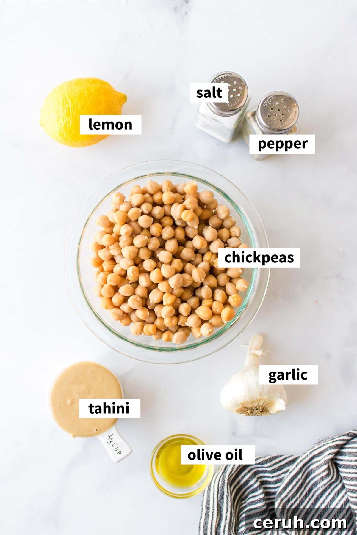 Ingredients needed for making a roasted garlic hummus recipe with tahini, lemon, chickpeas and olive oil.
